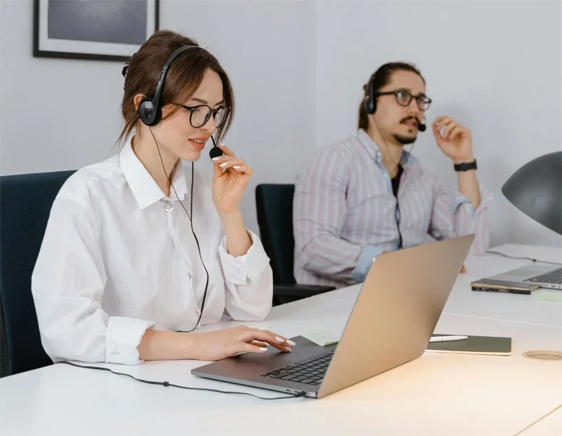 Un hombre y una mujer en un call center, realizando teletrabajo en España, concentrados en sus actividades