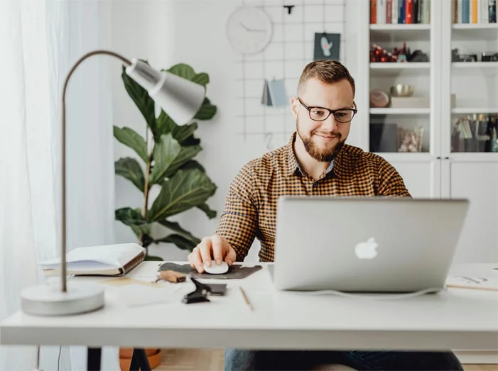 Hombre con gafas en un escritorio, concentrado en su computadora portátil, simbolizando el teletrabajo en España